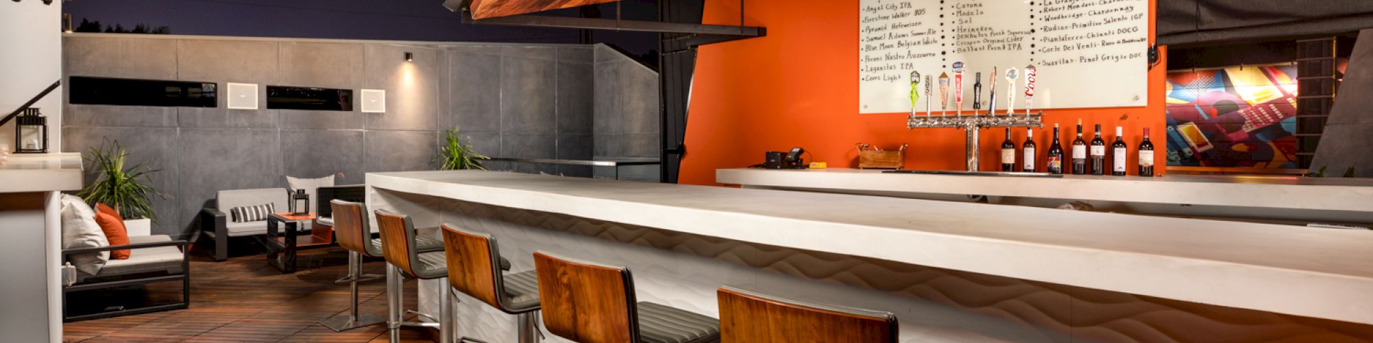 The image shows a modern bar interior with stools and a counter.