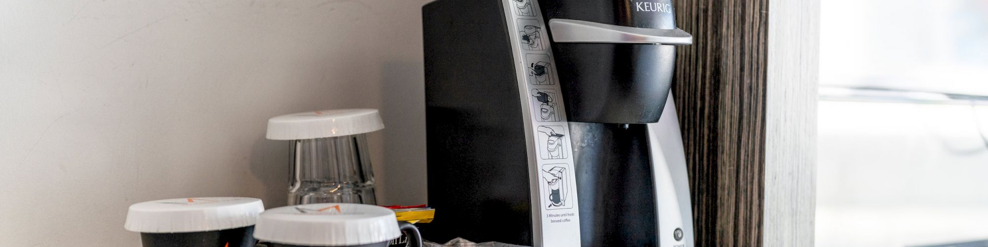 A coffee maker with cups and pods on a kitchen counter.