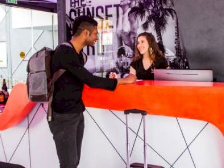 A man is checking in at a reception desk with a staff member.