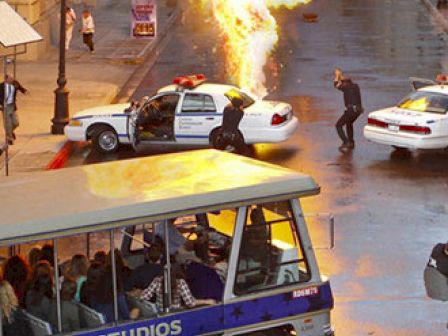 A stunt explosion near a tram with spectators at Universal Studios.