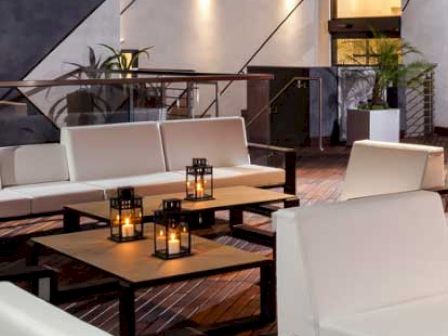 Modern lounge area with white sofas, wooden tables, and decorative lanterns.