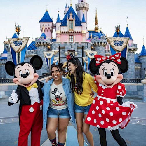 Two people pose with Mickey and Minnie Mouse in front of a castle at a Disney theme park, smiling and enjoying the moment.