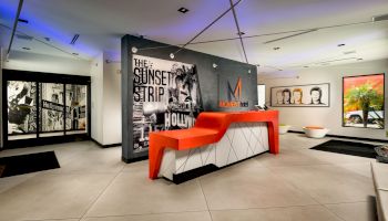 Modern room with art, orange bench, and decorative lighting.