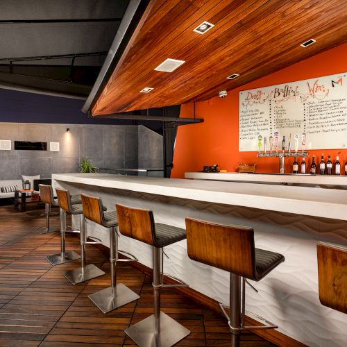 Modern bar interior with stools, counter, and menu board.