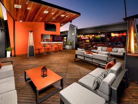 Modern outdoor patio with furniture, a kitchen area, and a sunset sky.